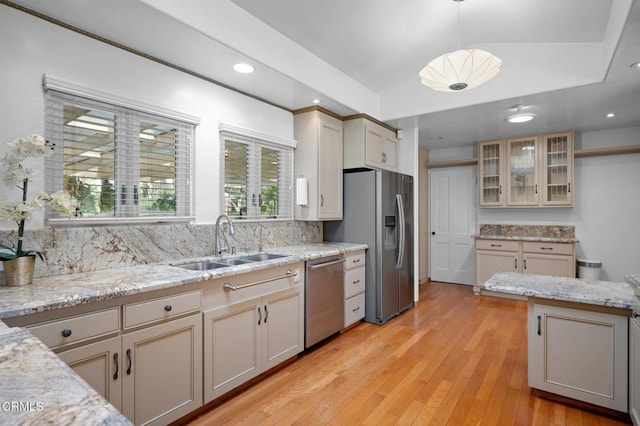 kitchen featuring cream cabinetry, stainless steel appliances, decorative backsplash, decorative light fixtures, and sink