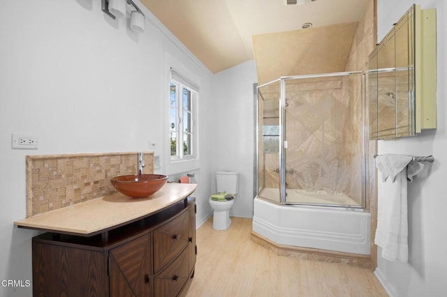 full bathroom with hardwood / wood-style floors, enclosed tub / shower combo, lofted ceiling, vanity, and toilet