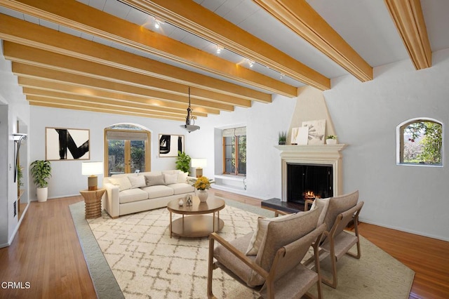 living room featuring wood-type flooring, a fireplace, beamed ceiling, and french doors