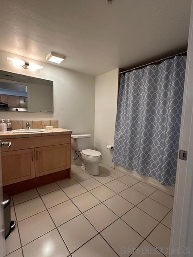 bathroom featuring tile patterned floors, vanity, toilet, and walk in shower