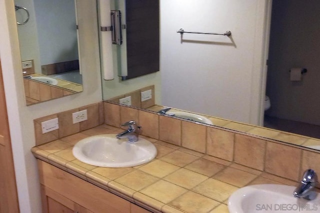 bathroom with vanity, toilet, and decorative backsplash