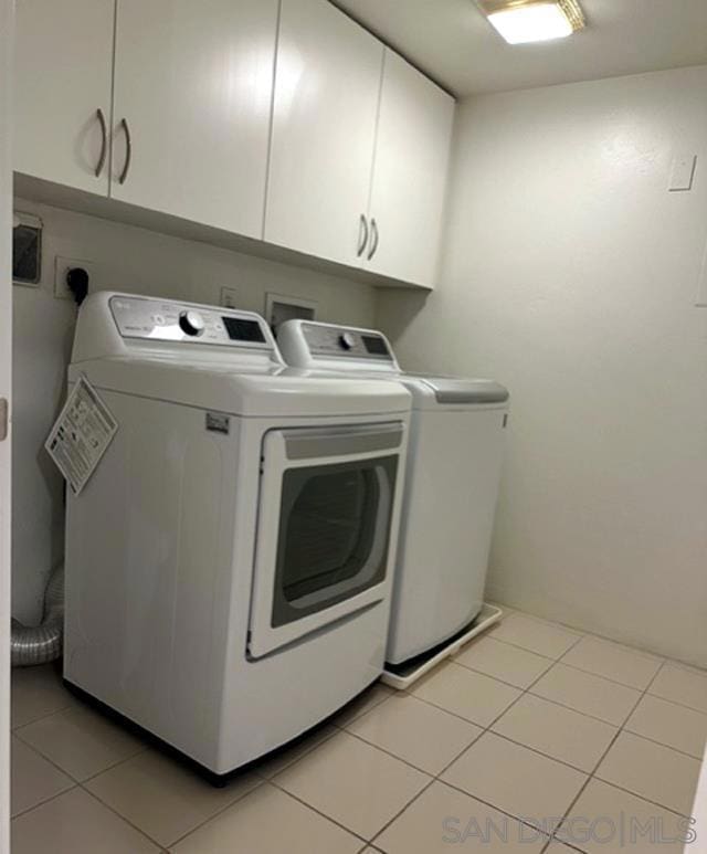 laundry room featuring washer and dryer, cabinets, and light tile patterned floors