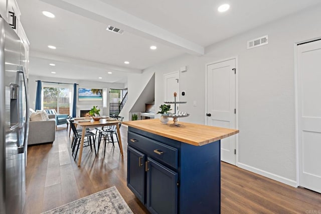 kitchen with stainless steel fridge, blue cabinetry, beam ceiling, a center island, and wood counters