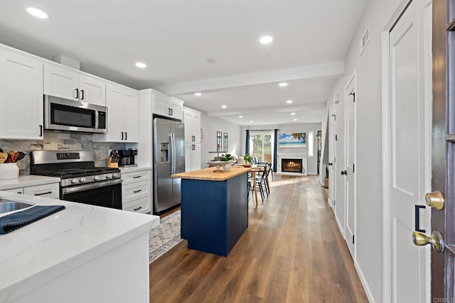 kitchen featuring butcher block countertops, dark wood-type flooring, white cabinetry, stainless steel appliances, and a kitchen island