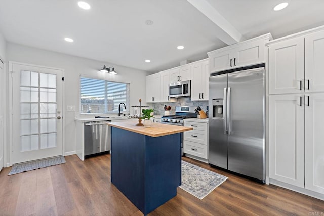 kitchen with appliances with stainless steel finishes, wood counters, white cabinetry, dark hardwood / wood-style flooring, and a center island