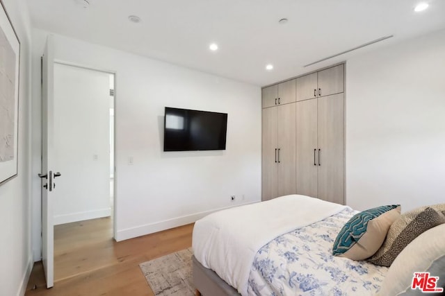 bedroom with light wood-type flooring and a closet