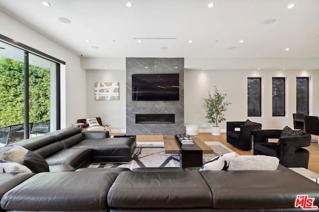 living room with a high end fireplace and light wood-type flooring