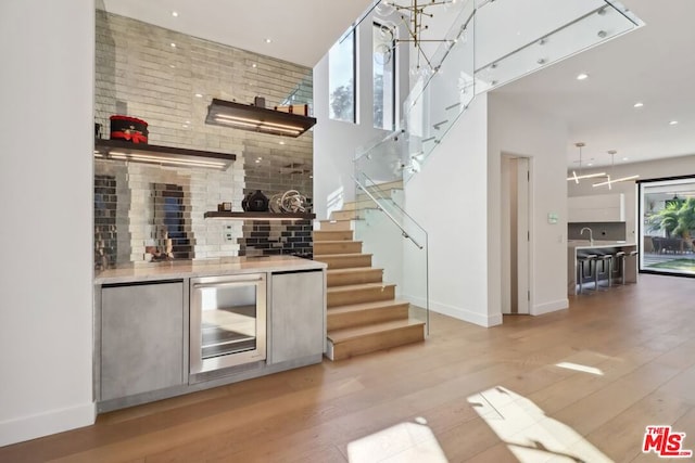 bar with light wood-type flooring and wine cooler