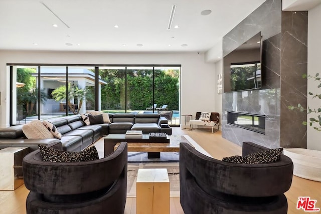 living room with a high end fireplace, wood-type flooring, and a wealth of natural light