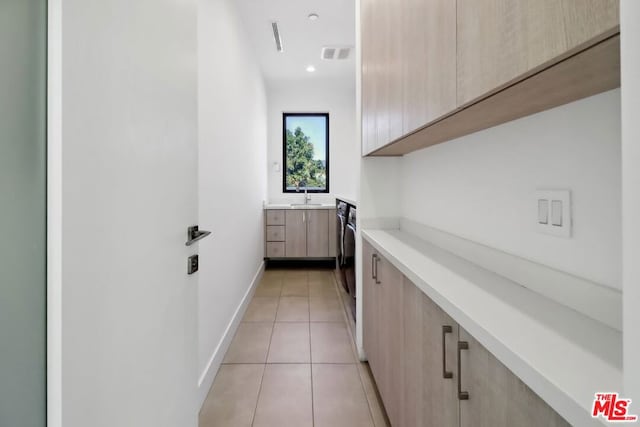 laundry area featuring cabinets, light tile patterned floors, washer / clothes dryer, and sink