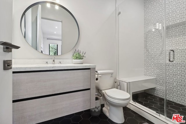 bathroom featuring tile patterned flooring, vanity, a shower with door, and toilet