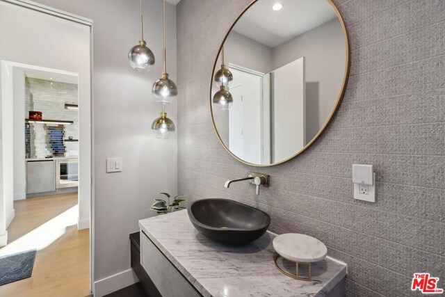 bathroom featuring hardwood / wood-style floors, vanity, and tile walls