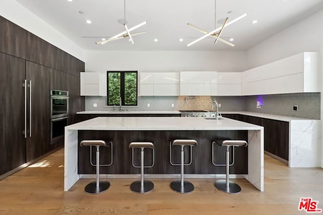 kitchen with white cabinets, pendant lighting, and a kitchen island with sink