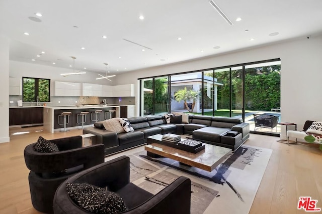 living room with light wood-type flooring, plenty of natural light, and sink