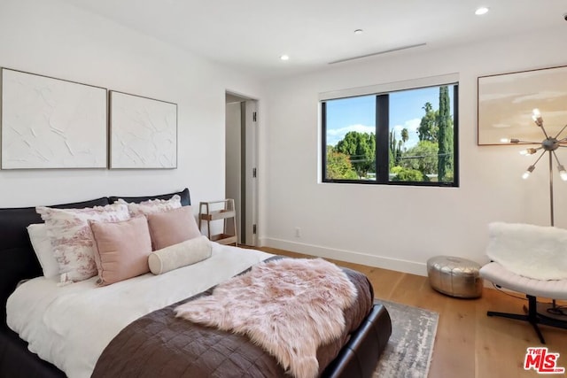 bedroom featuring an inviting chandelier and hardwood / wood-style flooring