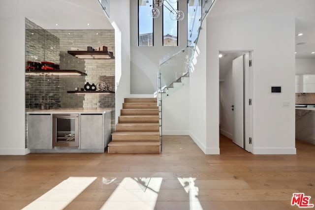 bar with decorative backsplash, light wood-type flooring, and wine cooler