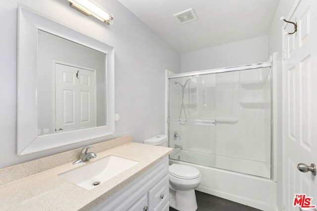 full bathroom featuring hardwood / wood-style floors, vanity, toilet, and bath / shower combo with glass door