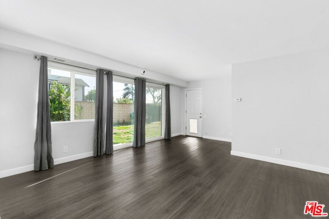 spare room with plenty of natural light and dark wood-type flooring