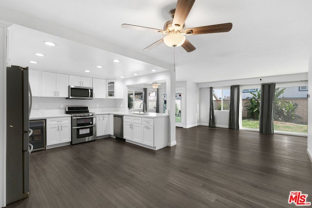 kitchen featuring stainless steel appliances, ceiling fan, sink, dark hardwood / wood-style floors, and white cabinetry