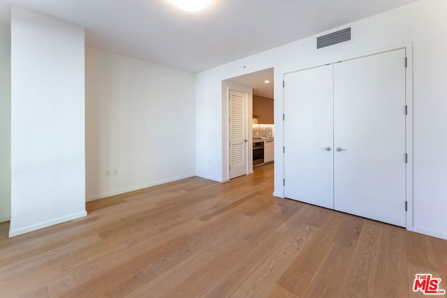 unfurnished bedroom with light wood-type flooring, sink, and a closet