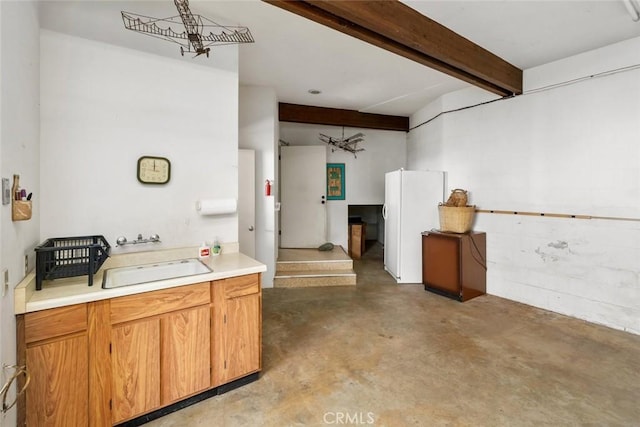 kitchen featuring beam ceiling, sink, and white fridge