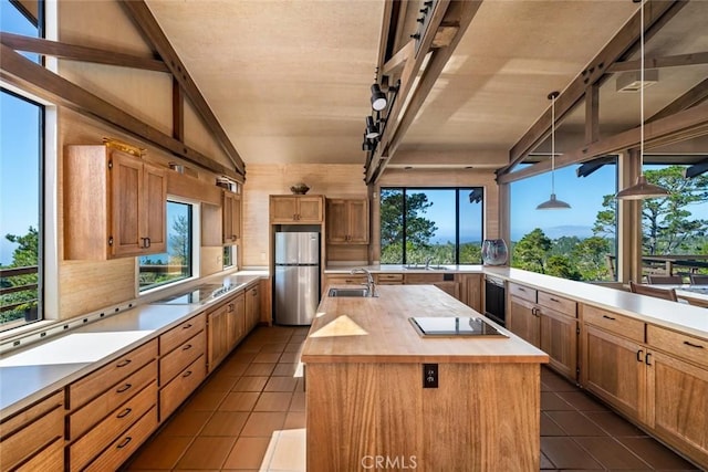 kitchen with hanging light fixtures, stainless steel fridge, a wealth of natural light, and a spacious island