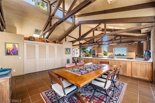 tiled dining room with vaulted ceiling with beams and a wealth of natural light