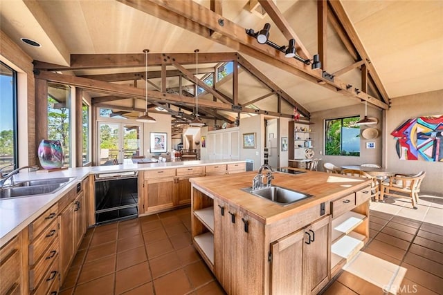 kitchen with black dishwasher, lofted ceiling with beams, hanging light fixtures, and sink