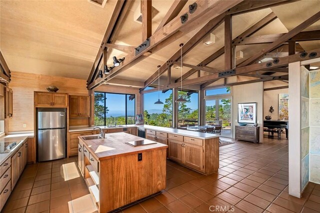 kitchen featuring stainless steel refrigerator, plenty of natural light, a spacious island, and vaulted ceiling with beams