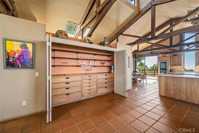 kitchen featuring dark tile patterned flooring, vaulted ceiling, and double oven