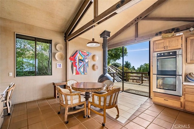 tiled dining room featuring vaulted ceiling with beams