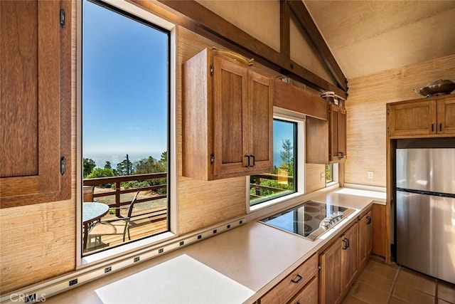 kitchen featuring tasteful backsplash, stainless steel fridge, stovetop, vaulted ceiling, and light tile patterned flooring