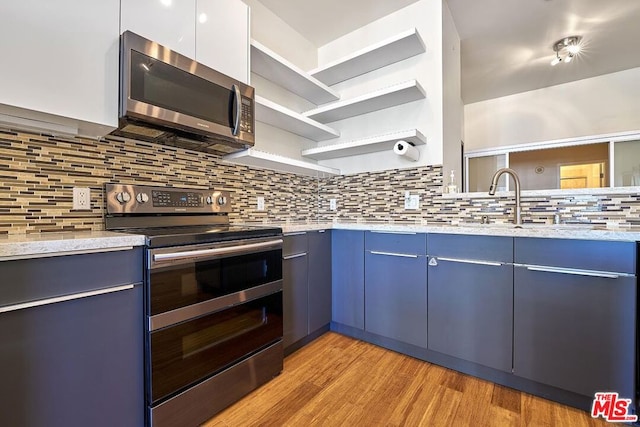 kitchen with tasteful backsplash, blue cabinets, stainless steel appliances, and light wood-type flooring