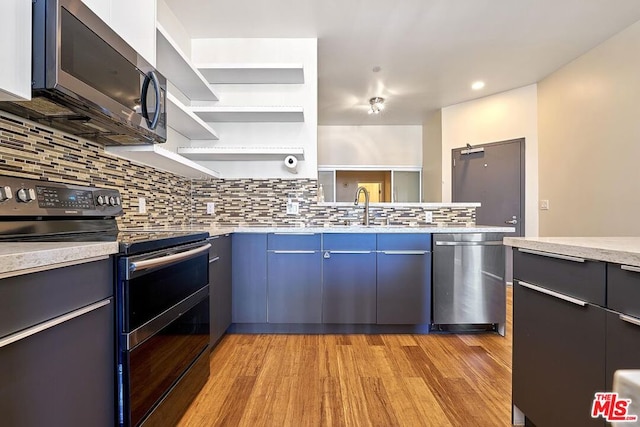 kitchen featuring decorative backsplash, light wood-type flooring, blue cabinetry, and appliances with stainless steel finishes