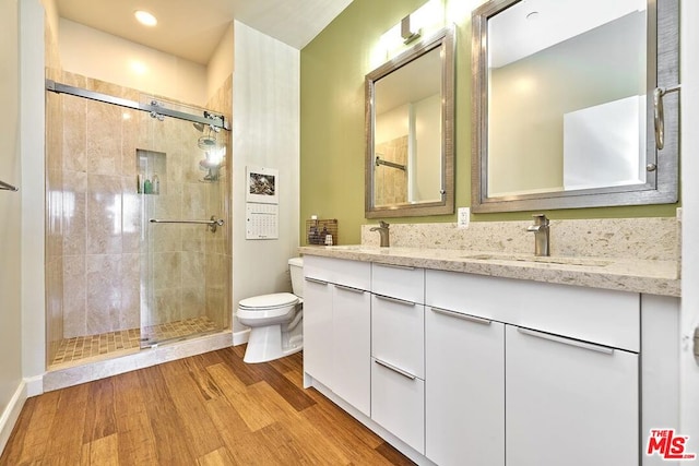 bathroom featuring hardwood / wood-style floors, vanity, toilet, and a shower with door