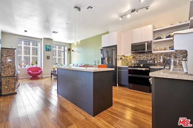 kitchen with stainless steel appliances, decorative light fixtures, a center island, light hardwood / wood-style floors, and white cabinetry