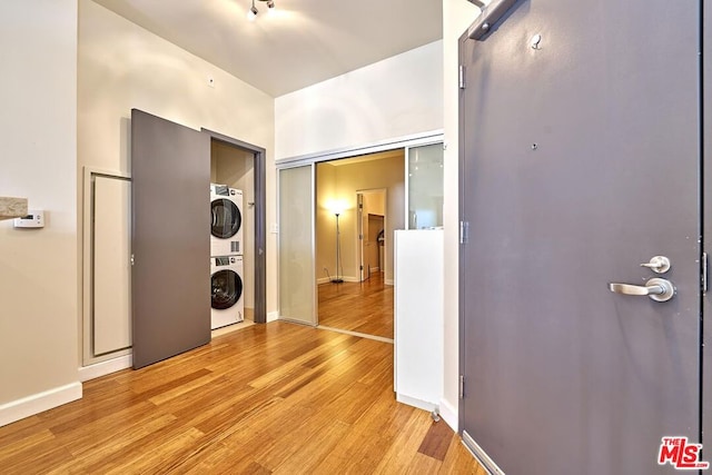 laundry room featuring light hardwood / wood-style flooring and stacked washer and clothes dryer