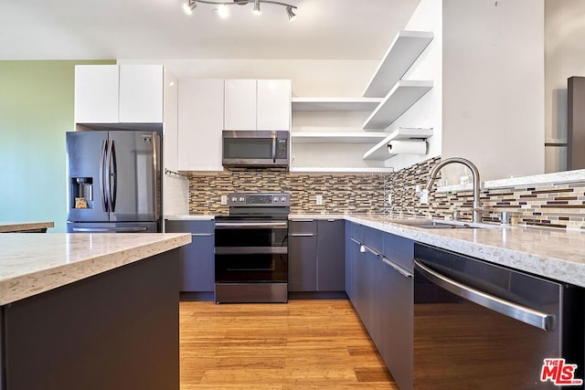 kitchen featuring light stone countertops, sink, stainless steel appliances, white cabinets, and light wood-type flooring