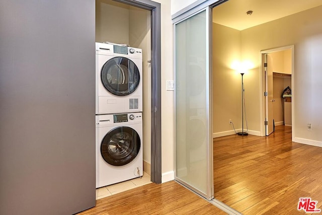 clothes washing area featuring light hardwood / wood-style floors and stacked washer / dryer