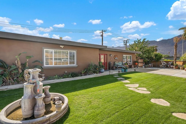 back of house featuring a mountain view, a patio area, and a yard