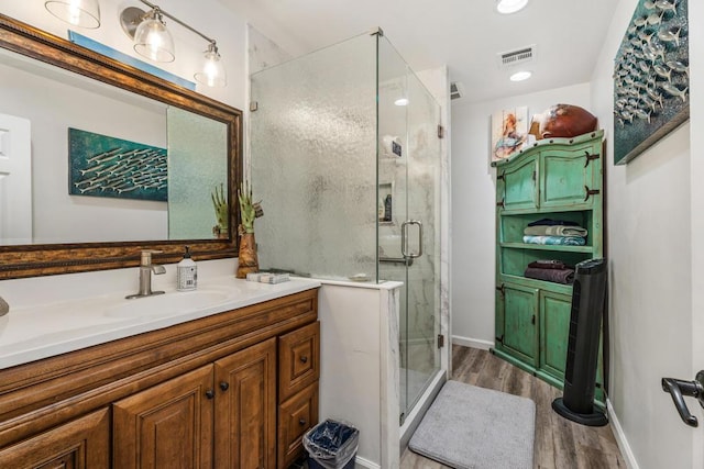 bathroom featuring hardwood / wood-style floors, vanity, and a shower with shower door