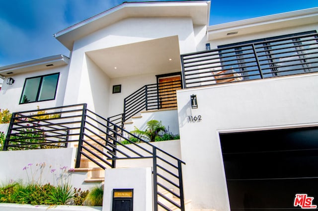 doorway to property with a balcony and a garage