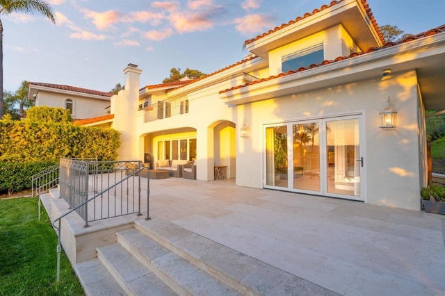 back house at dusk featuring outdoor lounge area and a patio area