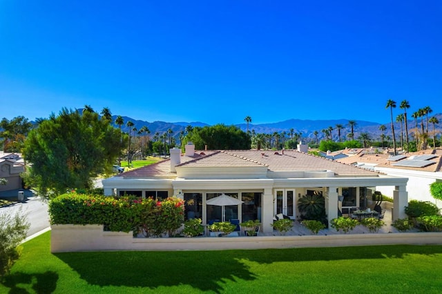 rear view of property with a mountain view and a lawn