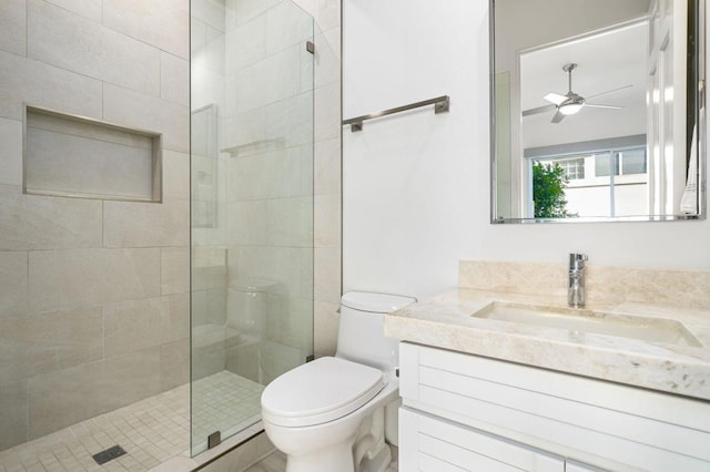 bathroom with tiled shower, ceiling fan, vanity, and toilet