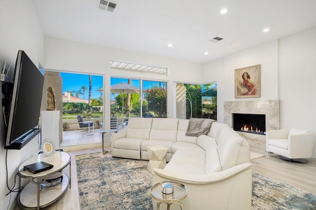 living room featuring a high end fireplace and light hardwood / wood-style flooring