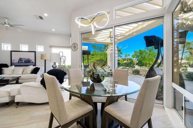 dining area with ceiling fan with notable chandelier and light hardwood / wood-style flooring