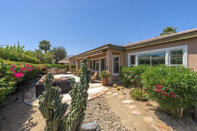 back of property with an outdoor living space and a patio area