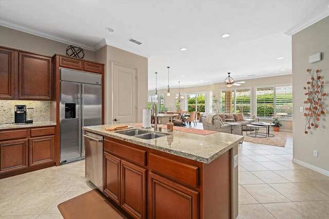 kitchen with a center island with sink, sink, ceiling fan, decorative backsplash, and appliances with stainless steel finishes