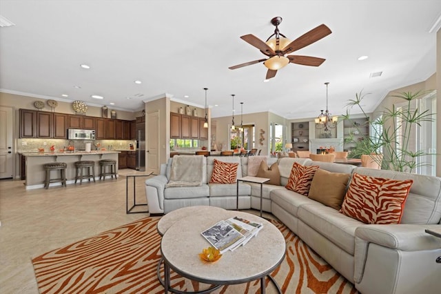 living room with ceiling fan with notable chandelier, light tile patterned floors, and crown molding